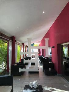 un restaurant aux murs rouges ainsi qu'une table et des chaises blanches dans l'établissement Hotel Eremo, à Soriano nel Cimino