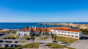 a large white building with a red roof and the ocean at Pousada de Sagres in Sagres