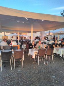 un grupo de personas sentadas en mesas bajo un paraguas en Piccolo Hotel, en Garda