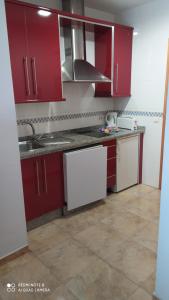 uma cozinha com armários vermelhos e um lavatório em Apartamentos Manuel Martin em Nerja