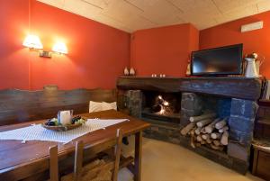 a living room with a fireplace and a table and a television at Hotel Can Blanc in Olot