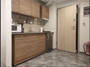 a kitchen with wooden cabinets and a microwave and a door at Cozy Studio, Athens city center in Athens