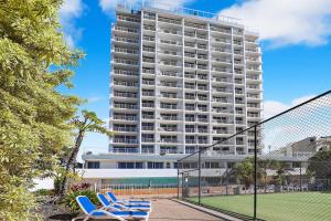 un edificio alto con sillas azules frente a una pista de tenis en Elouera Tower, en Maroochydore