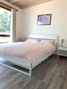 Un dormitorio con una cama blanca con sábanas rosas y una ventana en Ariel's Beach House, en Rye