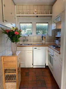 a kitchen with white cabinets and a vase of flowers at Rustig gelegen vakantiebungalow in Kortgene