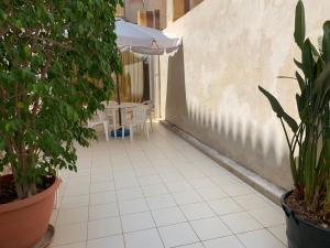 a patio with plants and a table and an umbrella at Casa dei gelsomini in Donnalucata