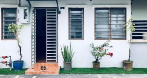 a white house with plants and a blue door at Sinar Ara homestay in Lunas