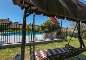 a hammock and a chair next to a pool at Swimming Pool Holiday Villa in Auckland