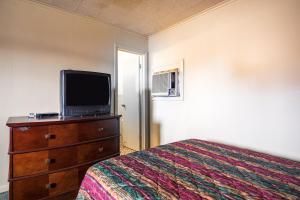 een slaapkamer met een bed en een tv op een dressoir bij OYO Hotel Holly Springs MS in Holly Springs