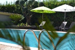 two green umbrellas sitting next to a swimming pool at Aquilamaior in Tragliata