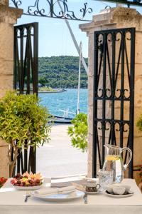 a table with a plate of food and a view of the water at Heritage Hotel Tisno in Tisno