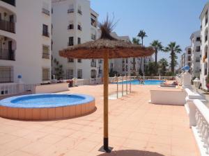 ein Strohschirm neben einem Pool in der Unterkunft Appartement Punta Almina 100 m from t h e sea in San Luis de Sabinillas