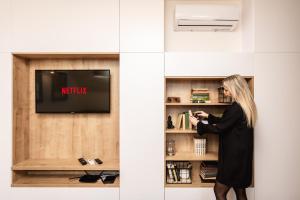 a woman in a black dress standing in front of a tv at FLEXIHOME SK - Komenskeho - private parking spot - ultra modern and stylish in Košice