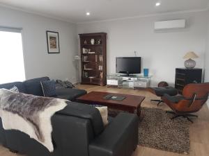 uma sala de estar com um sofá e cadeiras e uma televisão em Gilligan's Kangaroo Island em Baudin Beach