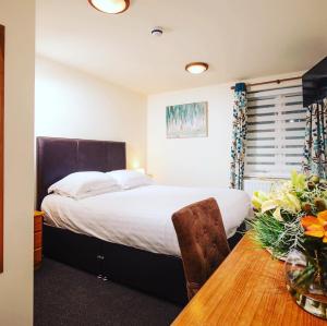 Un dormitorio con una cama y una mesa de madera. en The Cock Inn Hotel, en Sheering