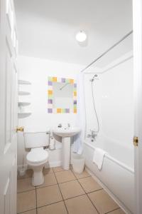 Un baño blanco con inodoro y lavabo. en The Cock Inn Hotel, en Sheering