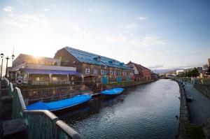 a river with boats docked next to some buildings at Otaru Tap Room & Hostel in Otaru