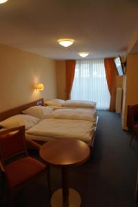 a room with four beds and a table and a chair at Hotel-Restaurant Weinhaus Grebel in Koblenz