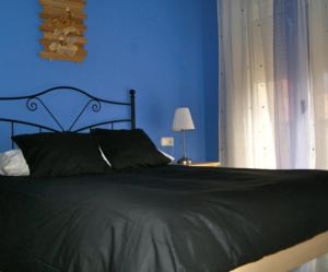 a blue bedroom with a black bed and a window at Apartamentos El Castañar in Hervás