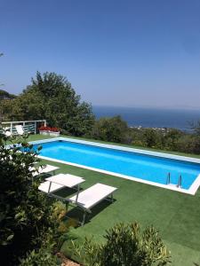 uma piscina com espreguiçadeiras brancas e o oceano em Sorrento Olive Tree Garden em Sorrento