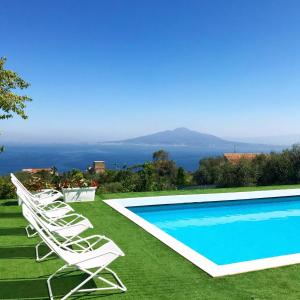 uma piscina com espreguiçadeiras e o oceano ao fundo em Sorrento Olive Tree Garden em Sorrento