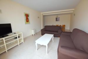 ein Wohnzimmer mit einem Sofa, einem TV und einem Tisch in der Unterkunft Apartamento Nou Fontana in Jávea