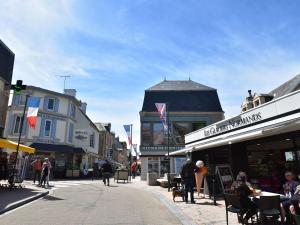 a street in a town with people sitting at tables at Comfortable apartment facing the museum in Arromanches-les-Bains