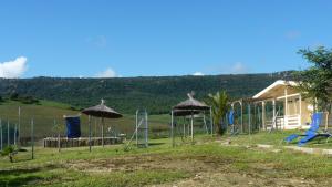 un parque infantil con columpios y sombrillas y una casa en Maryvacas Rural en La Zarzuela