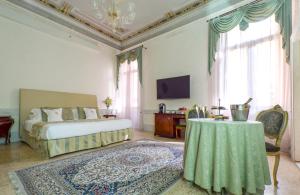 
a living room with a bed, chair, table and window at Hotel Palazzo Vitturi in Venice
