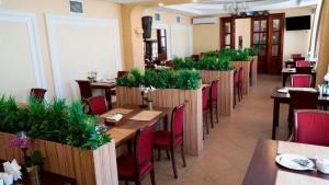 ヴォログダにあるHotel Vologdaの木製のテーブルと椅子、植物のあるレストラン