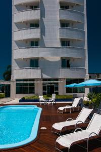 a hotel with a swimming pool and chairs and a building at Favorita Golden Hotel e Eventos in São José