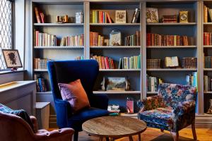 una stanza con due sedie e una libreria con libri di Hotel Indigo - Stratford Upon Avon, an IHG Hotel a Stratford-upon-Avon