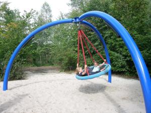 zwei Kinder spielen auf einer Schaukel auf einem Spielplatz in der Unterkunft Camping Baalse Hei in Turnhout