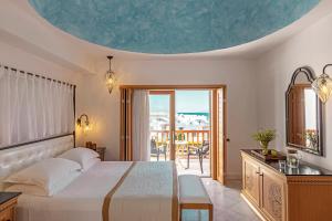 a bedroom with a large bed and a balcony at Mitsis Selection Blue Domes in Kardamaina