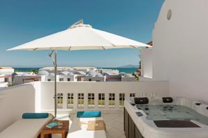 a hot tub on a balcony with an umbrella at Mitsis Selection Blue Domes in Kardamaina
