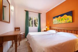 a bedroom with two beds and a desk and a window at PINOS ALTOS 04 in Cala de Sant Vicenc +12 photos