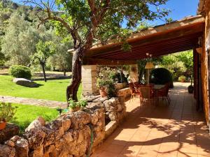 a patio with a stone wall and a wooden pergola at Finca Can Trui in Pollença