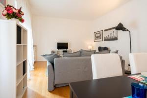un soggiorno con divano grigio e sedie bianche di Buzzi Flexyrent Apartment a Milano