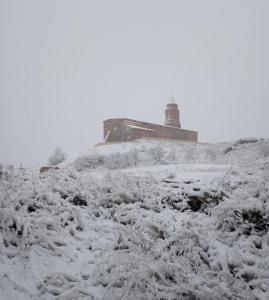 Olvés的住宿－Casa Isabel，一座有雪覆盖的山丘,后面是一座灯塔