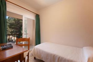 a bedroom with a bed and a desk and a window at PINOS ALTOS 11 in Cala de Sant Vicenc +14 photos
