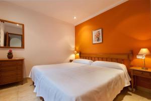 a bedroom with a white bed with an orange wall at PINOS ALTOS 13 in Cala de Sant Vicenc +17 photos