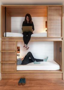 a woman sitting on top of a bunk bed at Toc Hostel Granada in Granada