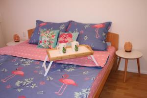 Una cama con una bandeja con una mesa. en Pink Flamingo Nest - unique design apartment, en Senta