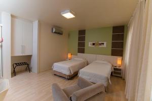 a hospital room with two beds and a chair at Locanda Hotel in Novo Hamburgo