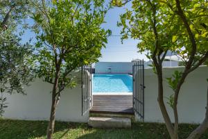 an open gate leading to a swimming pool through trees at La Locanda Del Carrubo in Mattinata