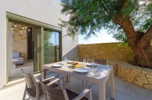 a table and chairs on a patio with a tree at Zefyros Apartments and House in Kissamos