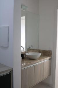 um banheiro com uma pia e um espelho em Nosso Cantinho Canasvieiras em Florianópolis mais 56 fotografias
