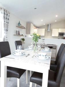 a white table with black chairs in a kitchen at Clearwater lodge Widemouth sands in Poundstock +35 photos