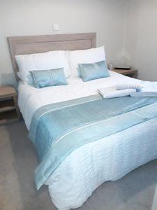 a large white bed with blue pillows on it at Clearwater lodge Widemouth sands in Poundstock