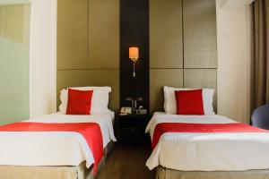 a hotel room with two beds with red pillows at Onomo Hotel Dar es Salaam in Dar es Salaam